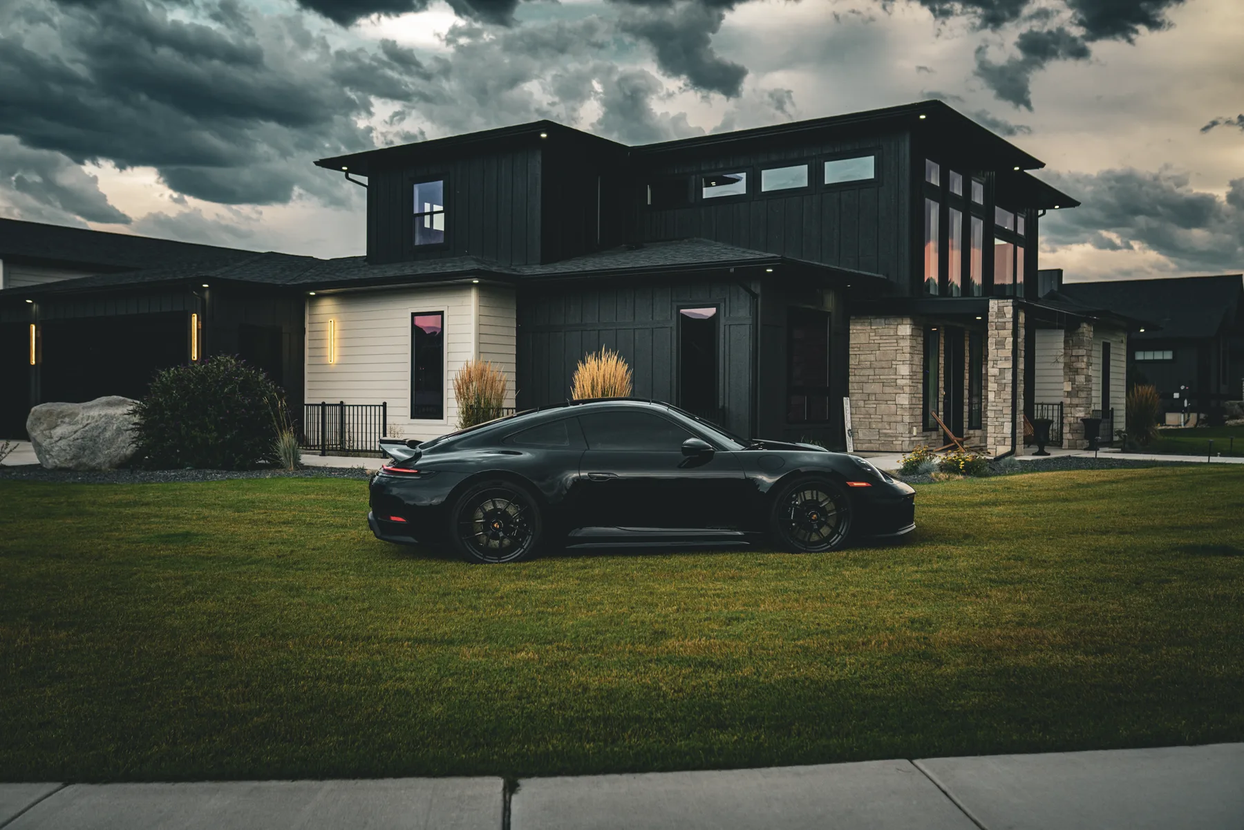 Black Porsche 911 parked on the front lawn of Matt's house under storm clouds